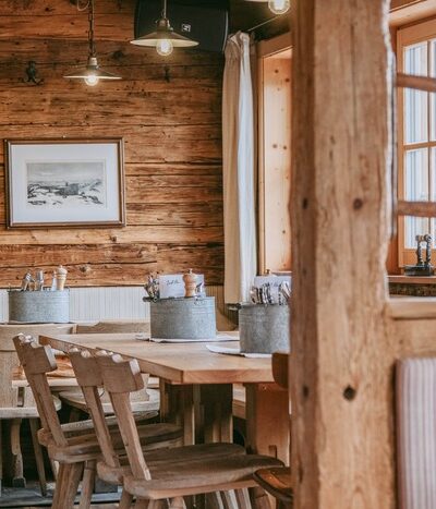 Die Seidlalm von innen: rustikale Holztische und Stühle.