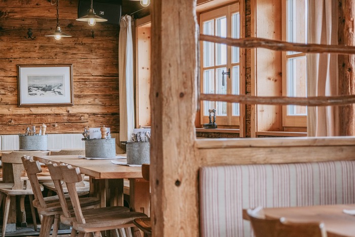 Die Seidlalm von innen: rustikale Holztische und Stühle.