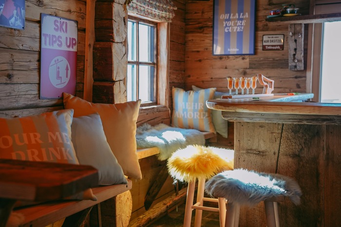 Die Schilala Aprés Ski Hütte von innen, mit bunten Kissen und Postern an der Wand.