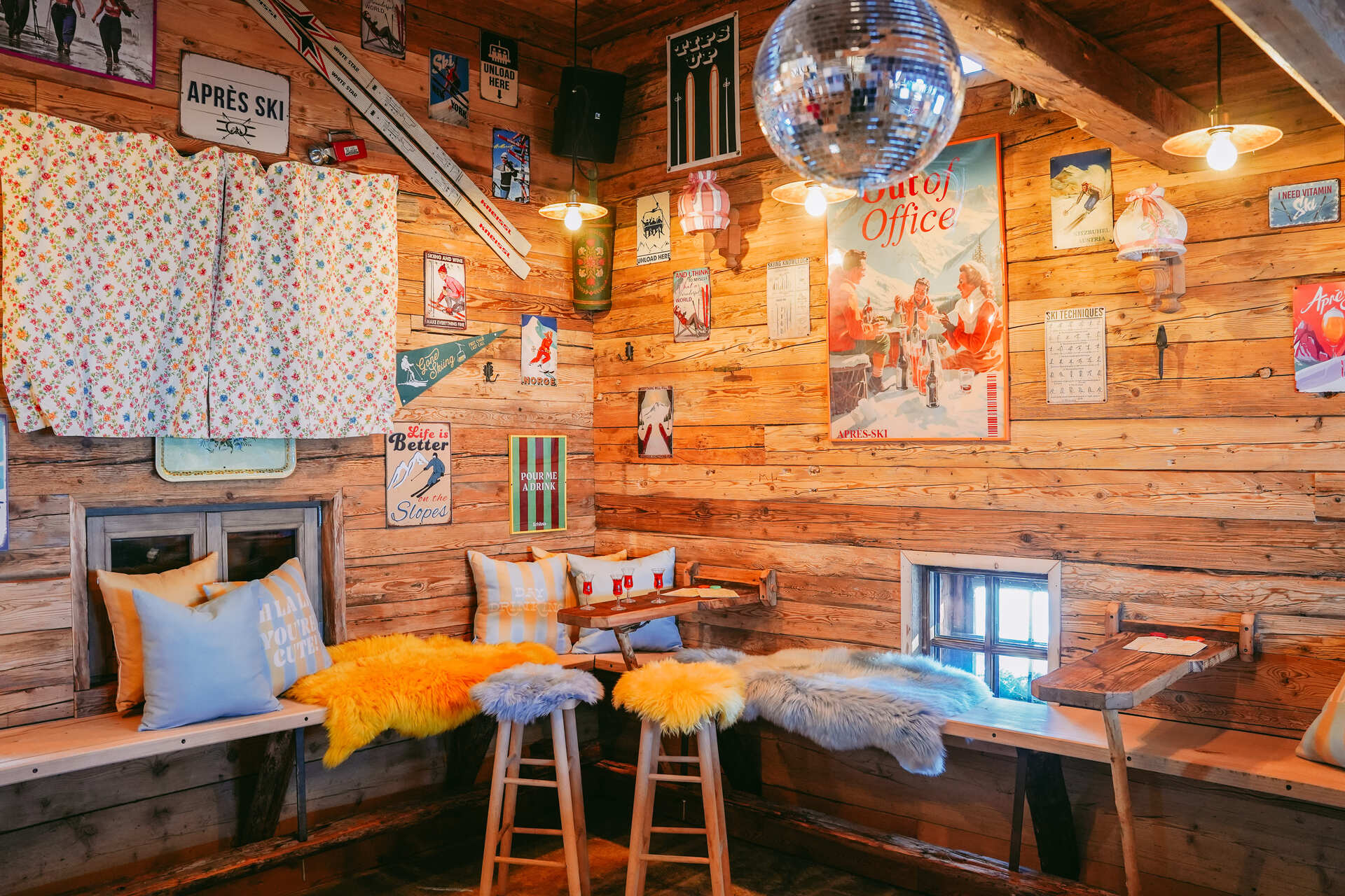 Die Schilala Aprés Ski Hütte von innen, mit bunten Kissen und Postern an der Wand.