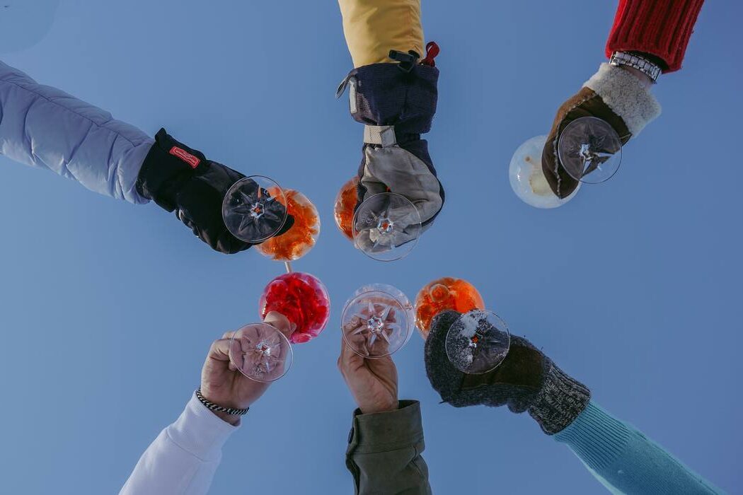 Blick von unten in den Himmel, mit Sicht auf mehrere Personen die mit Getränken anstossen.