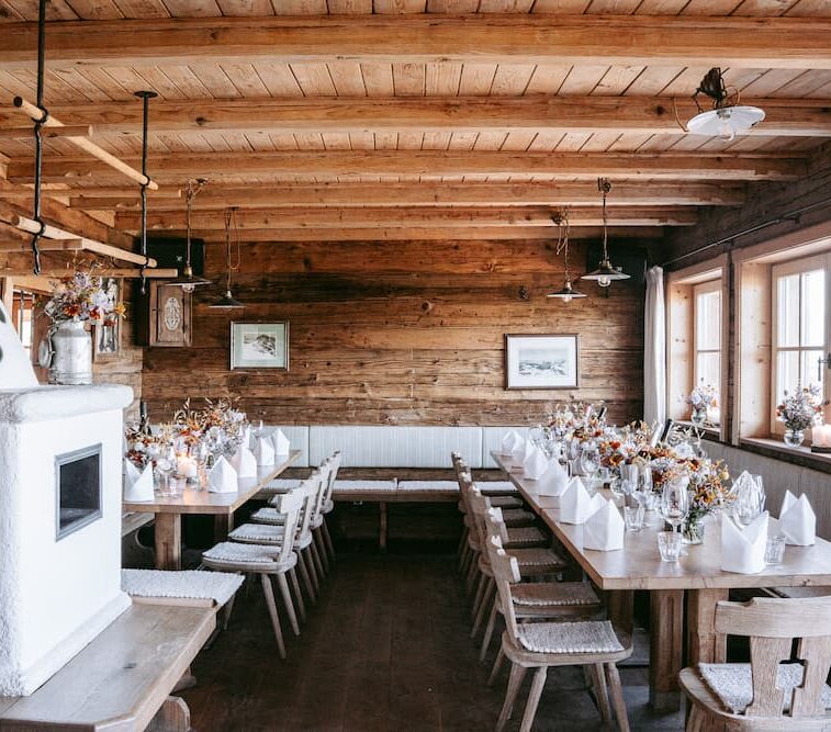 Seidlalm Events auf der Schilala Aprés Ski Hütte - Terasse mit Bänken und Tischen und Orange/ Grün gestreiften Schilala Kissen.